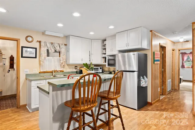 a kitchen with stainless steel appliances a refrigerator a stove a sink dishwasher and a refrigerator with wooden floor