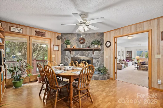 a view of a dining room and livingroom with furniture wooden floor a chandelier fan a flat screen tv and a large window