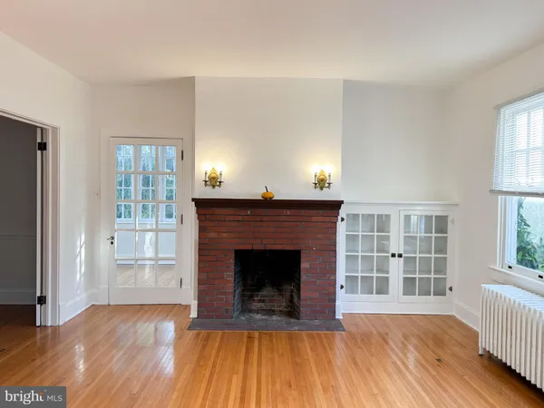 an empty room with wooden floor fireplace and windows
