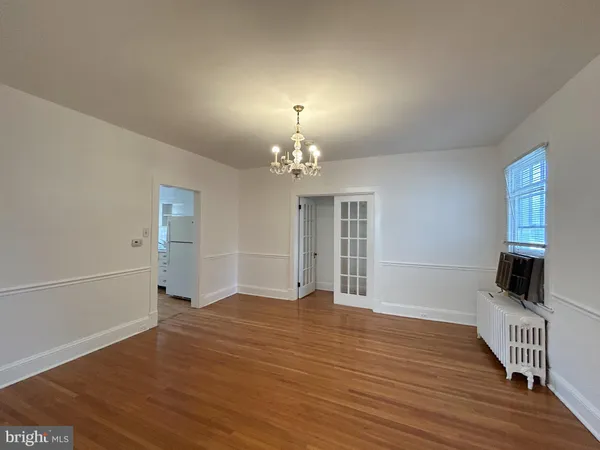 a view of an empty room with window and wooden floor