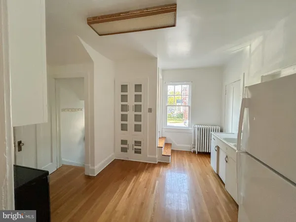 a kitchen with a refrigerator and a wooden floor