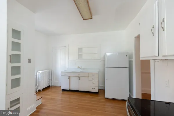 a view of an empty room with wooden floor and cabinet