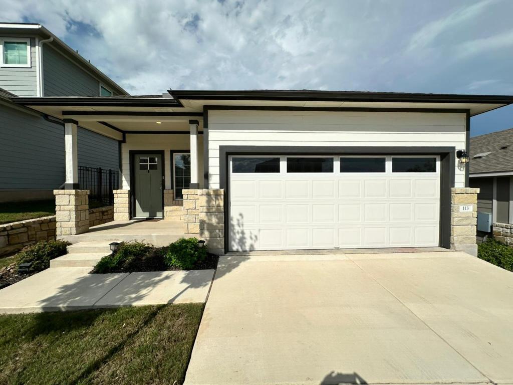113 Merrick Road Georgetown, TX 78628 - Photo 1 of 1 View of front facade with driveway, a porch, a garage, and stone siding