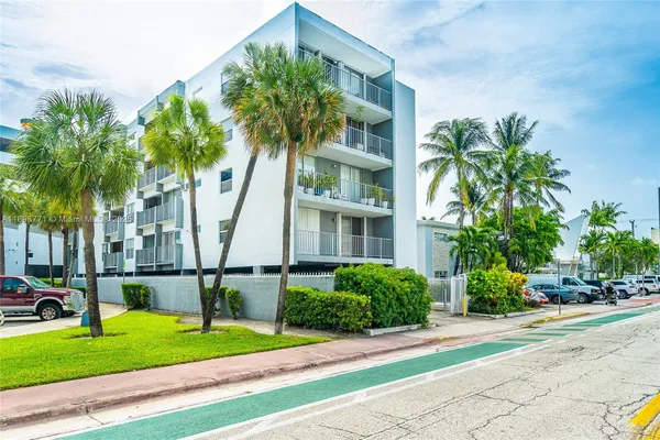 a front view of multi story residential apartment building with yard and green space