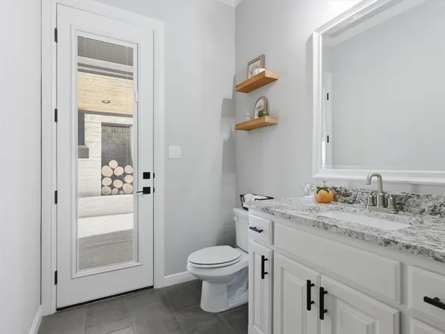 a bathroom with a granite countertop toilet sink and mirror