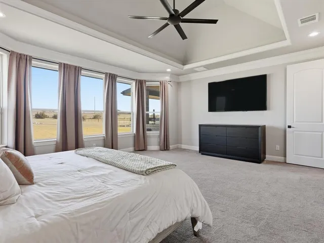 a spacious bedroom with a large bed and a flat screen tv