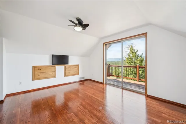 a view of a room with wooden floor and a ceiling fan