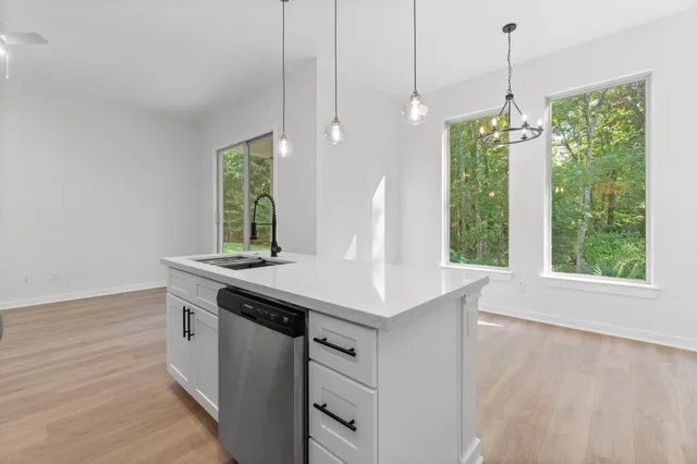 a kitchen with stainless steel appliances granite countertop a sink a stove and a wooden floors