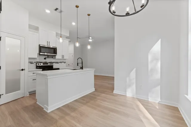 a large white kitchen with a refrigerator a stove a fireplace and a flat screen tv