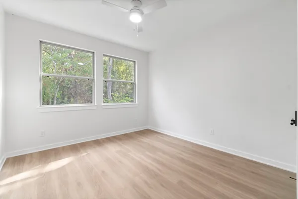 an empty room with wooden floor and windows