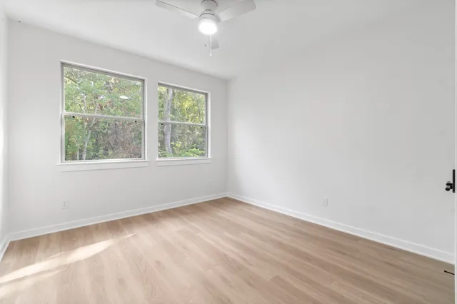 an empty room with wooden floor and windows
