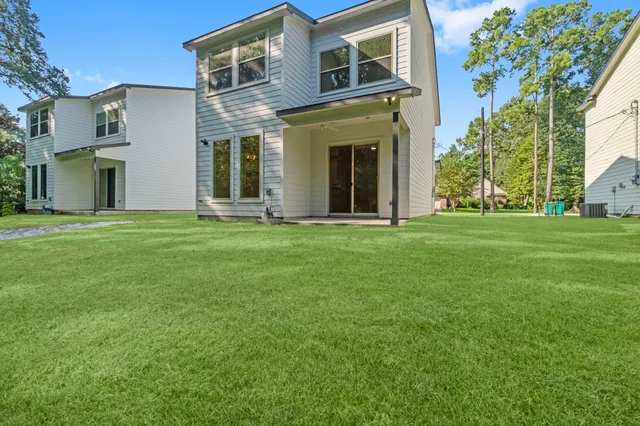 a view of a brick house with a big yard and large trees