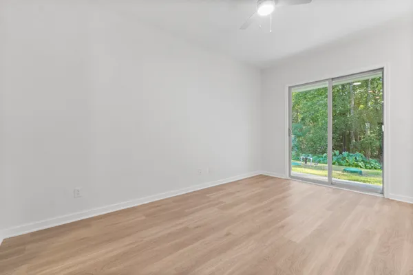 a view of an empty room with wooden floor and a window