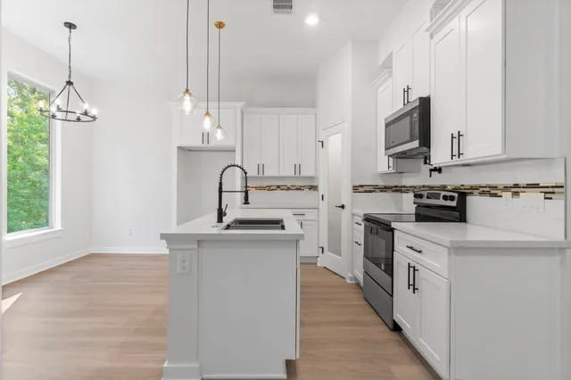 a kitchen with white cabinets appliances and a sink
