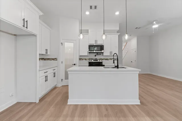 a large kitchen with cabinets wooden floor stainless steel appliances and a couch