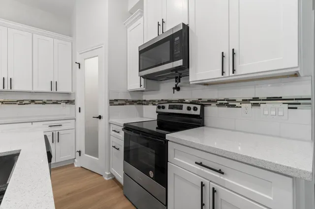 a kitchen with stainless steel appliances white cabinets and a stove a microwave oven with white cabinets