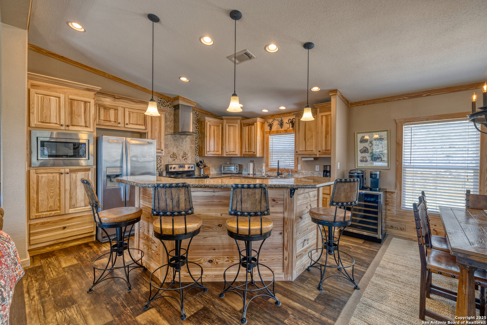 2242 Patterson Creek Road Leakey, TX 78873 - Photo 45 of 57 a kitchen with stainless steel appliances kitchen island granite countertop a stove a refrigerator and a dining table with wooden floor