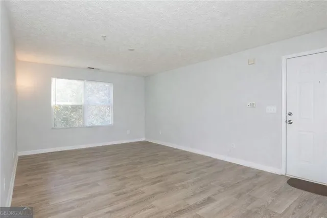 an empty room with wooden floor and windows
