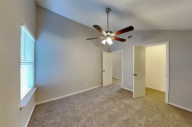 a view of an empty room with chandelier fan and fire place