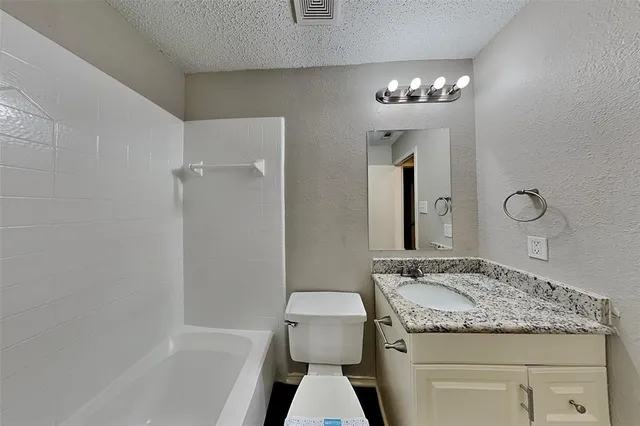 a bathroom with a granite countertop sink a toilet and shower