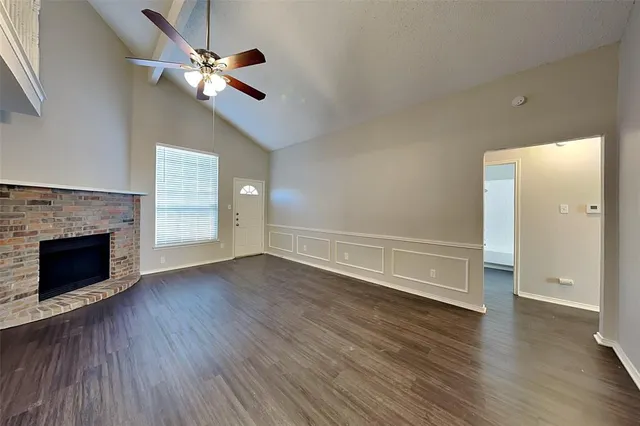 an empty room with wooden floor fireplace and ceiling fan