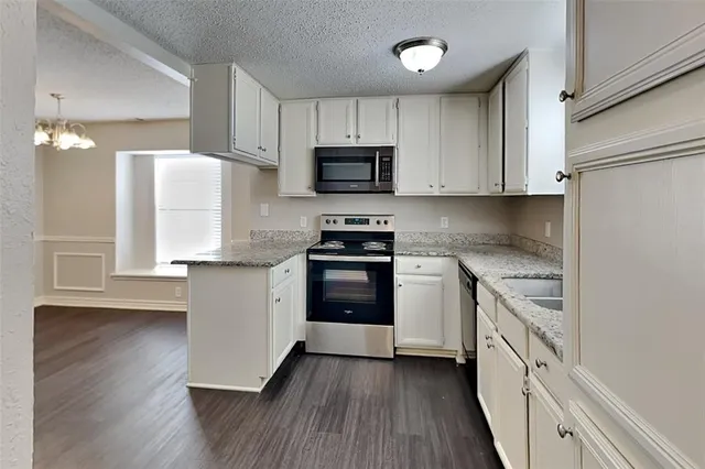 a kitchen with granite countertop white cabinets and stainless steel appliances