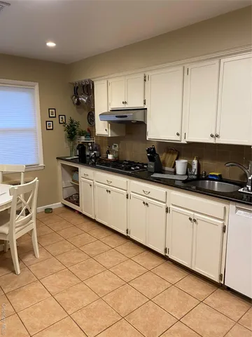 a kitchen with granite countertop a sink and white cabinets