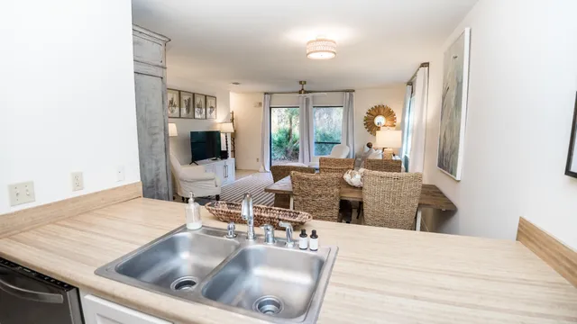 a kitchen with a sink dishwasher a dining table and chairs with wooden floor