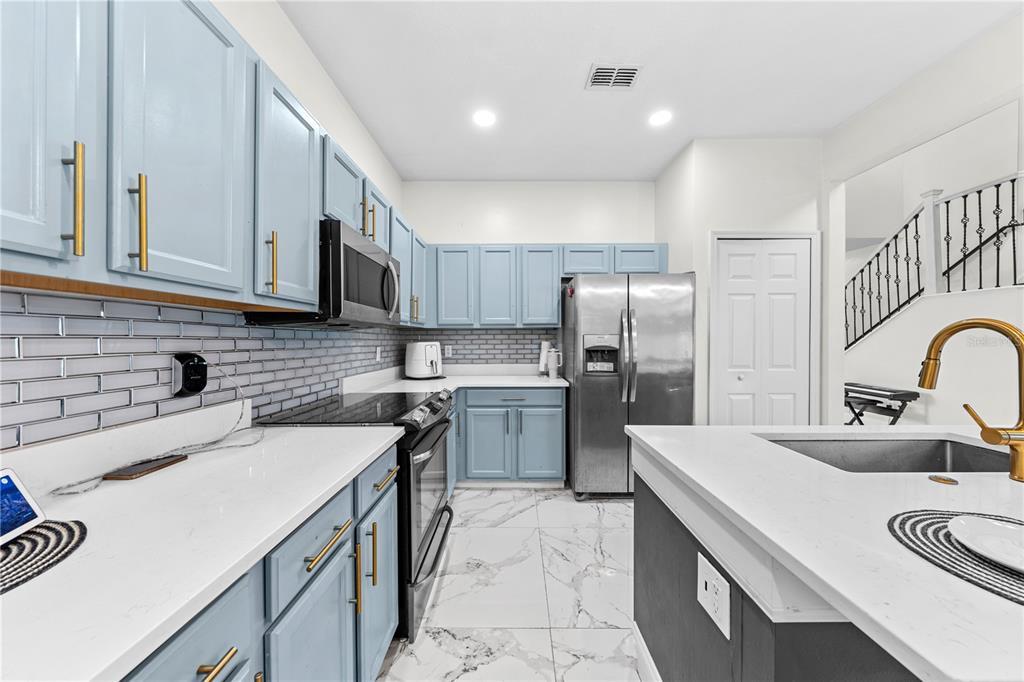 4301 Presidio Way Kissimmee, FL 34746 - Photo 13 of 50 a kitchen with a sink a stove a refrigerator and cabinets