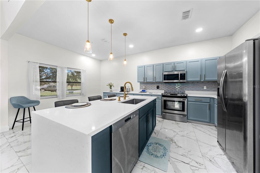 4301 Presidio Way Kissimmee, FL 34746 - Photo 16 of 50 a kitchen with a sink a kitchen island and stainless steel appliances