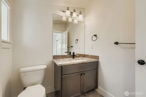 a bathroom with a granite countertop bathtub shower sink vanity mirror and toilet