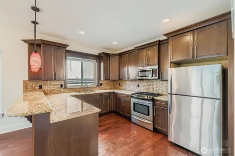 a kitchen with stainless steel appliances granite countertop a refrigerator a stove a sink dishwasher and a refrigerator with wooden floor