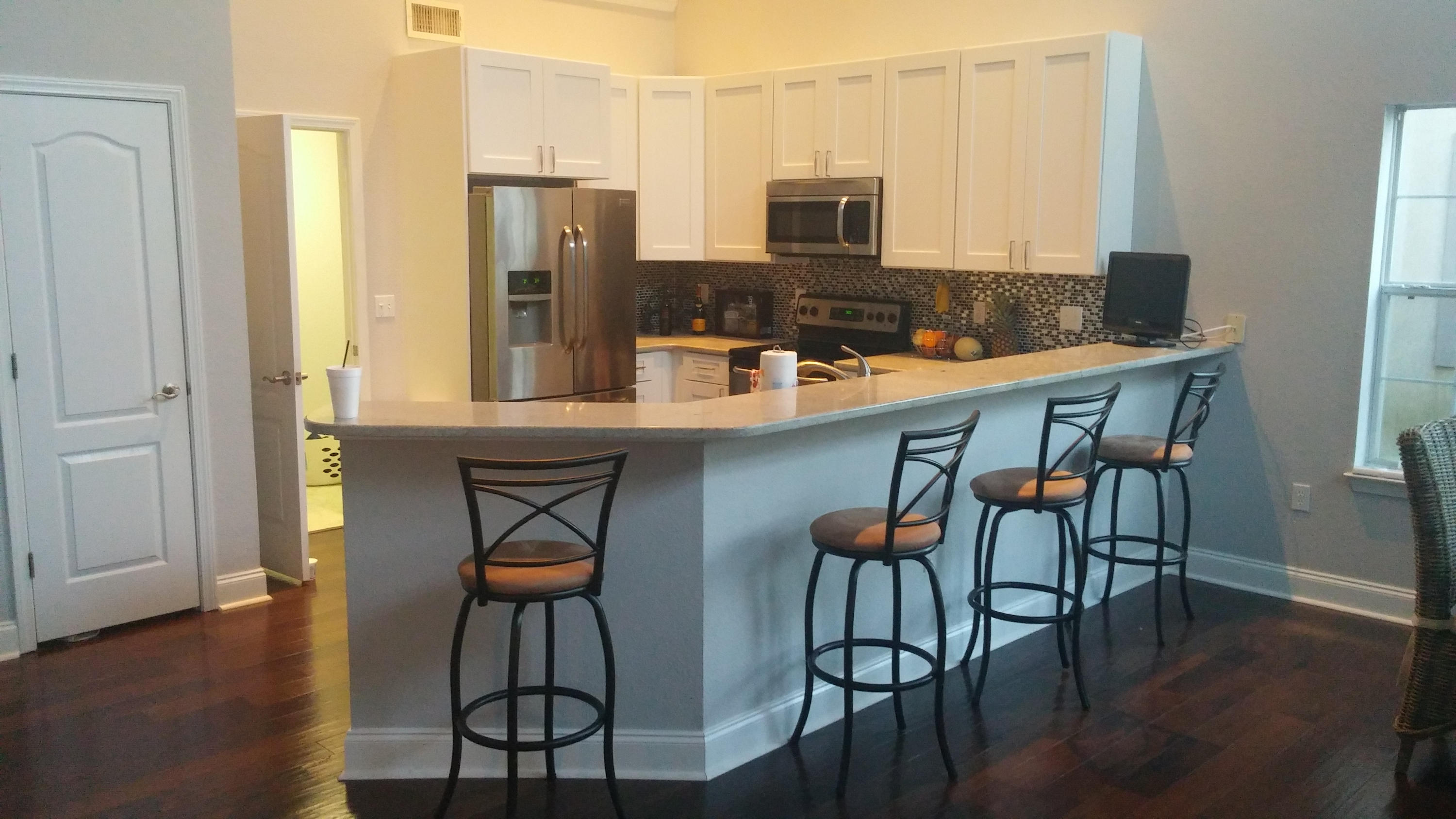 175 Loblolly Bay Drive Santa Rosa Beach, FL 32459 - Photo 6 of 11 a kitchen with stainless steel appliances granite countertop a stove a refrigerator a sink a dining table and chairs with wooden floor