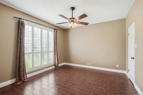a view of an empty room with window and chandelier fan