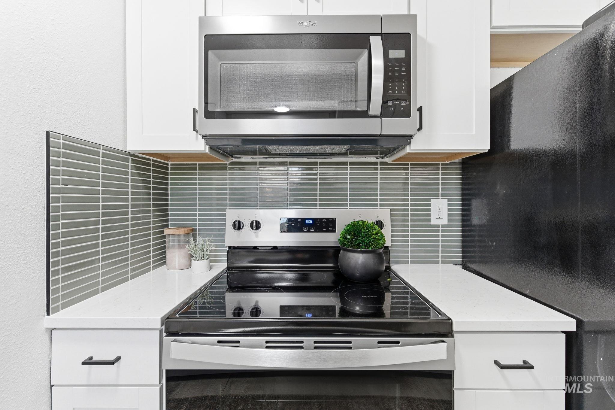 2224 Rachel Circle Boise, ID 83706 - Photo 18 of 50 Modern kitchen featuring a stainless steel range with a black cooktop, a coordinating stainless steel microwave, white cabinetry with matte black hardware, white countertops, and a gray horizontal tile backsplash