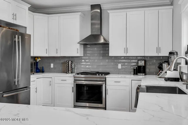 a kitchen with stainless steel appliances granite countertop a stove a refrigerator and a white cabinets