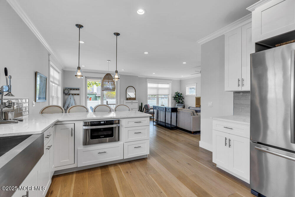 601 Ocean Road Spring Lake Heights, NJ 07762 - Photo 5 of 41 a kitchen with stainless steel appliances a stove a sink dishwasher a refrigerator and white cabinets with wooden floor