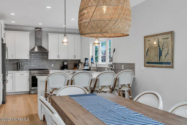a kitchen with stainless steel appliances granite countertop a table chairs sink and cabinets