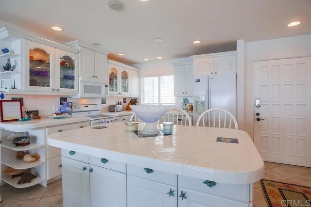 a kitchen with a sink dishwasher and white cabinets with wooden floor