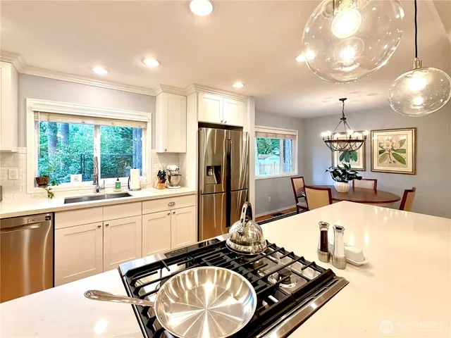 a kitchen with a stove a sink dishwasher and a refrigerator with wooden floor