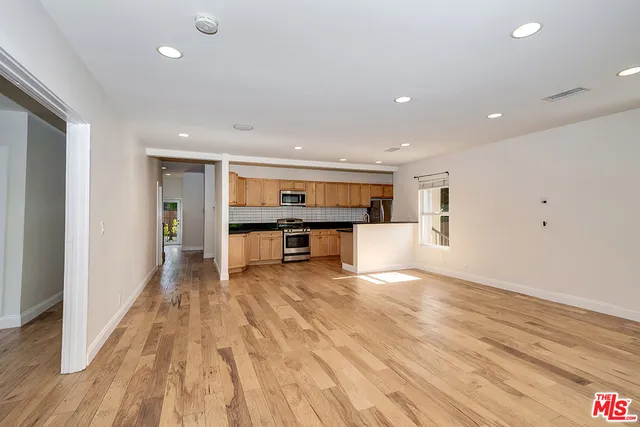 a view of a big room with wooden floor and windows