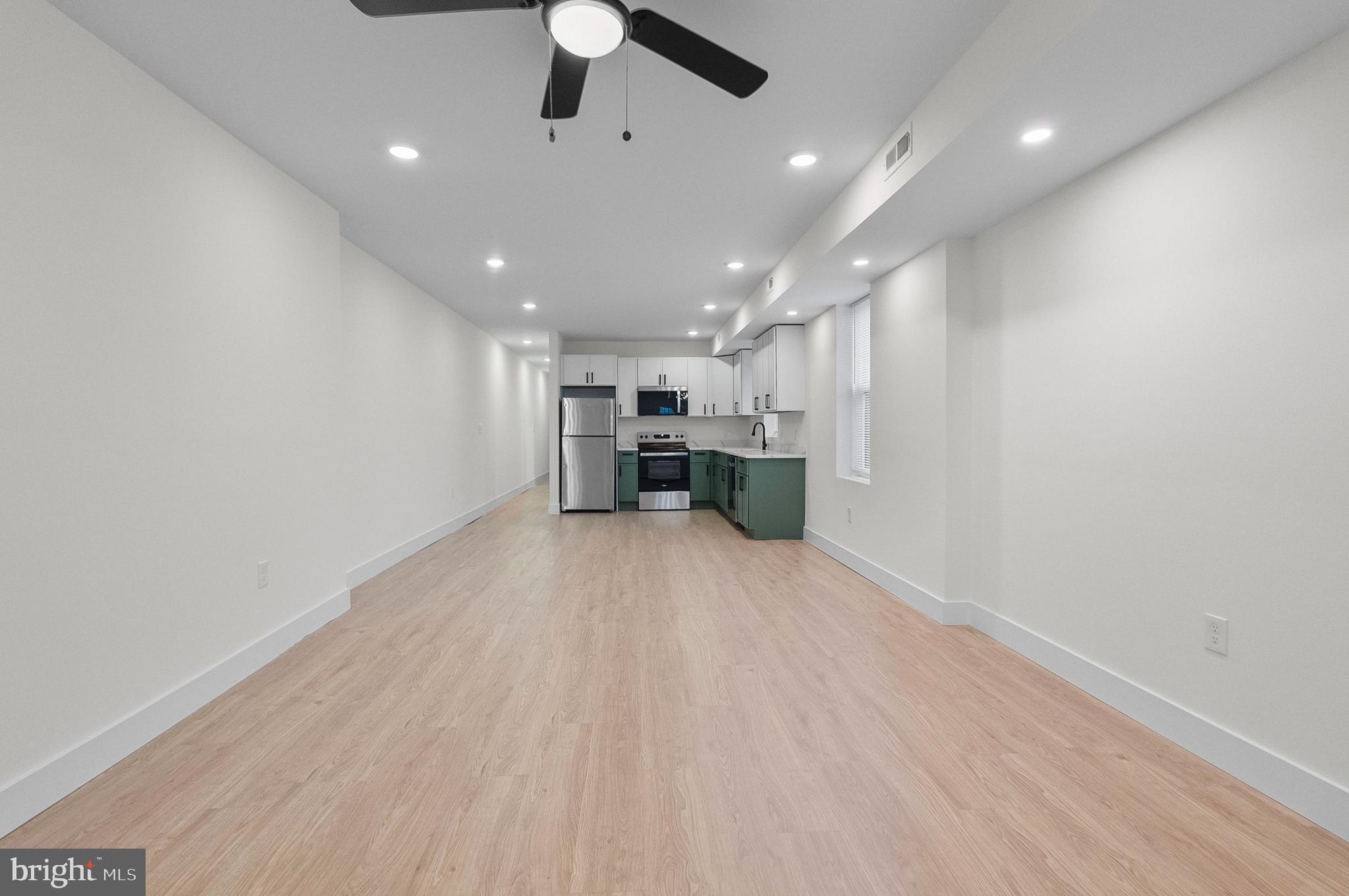 2200 East Fayette Street Baltimore, MD 21231 - Photo 2 of 23 an empty room with wooden floor a ceiling fan and windows