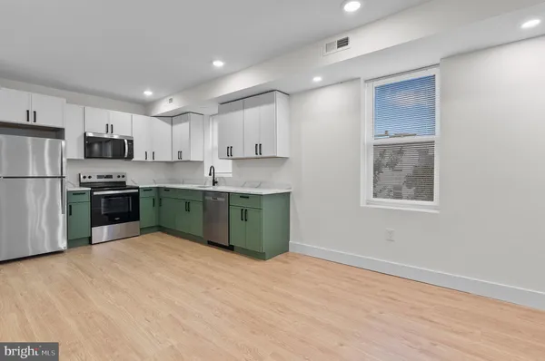 a kitchen with stainless steel appliances granite countertop a stove top oven a refrigerator a sink and dishwasher with wooden floor