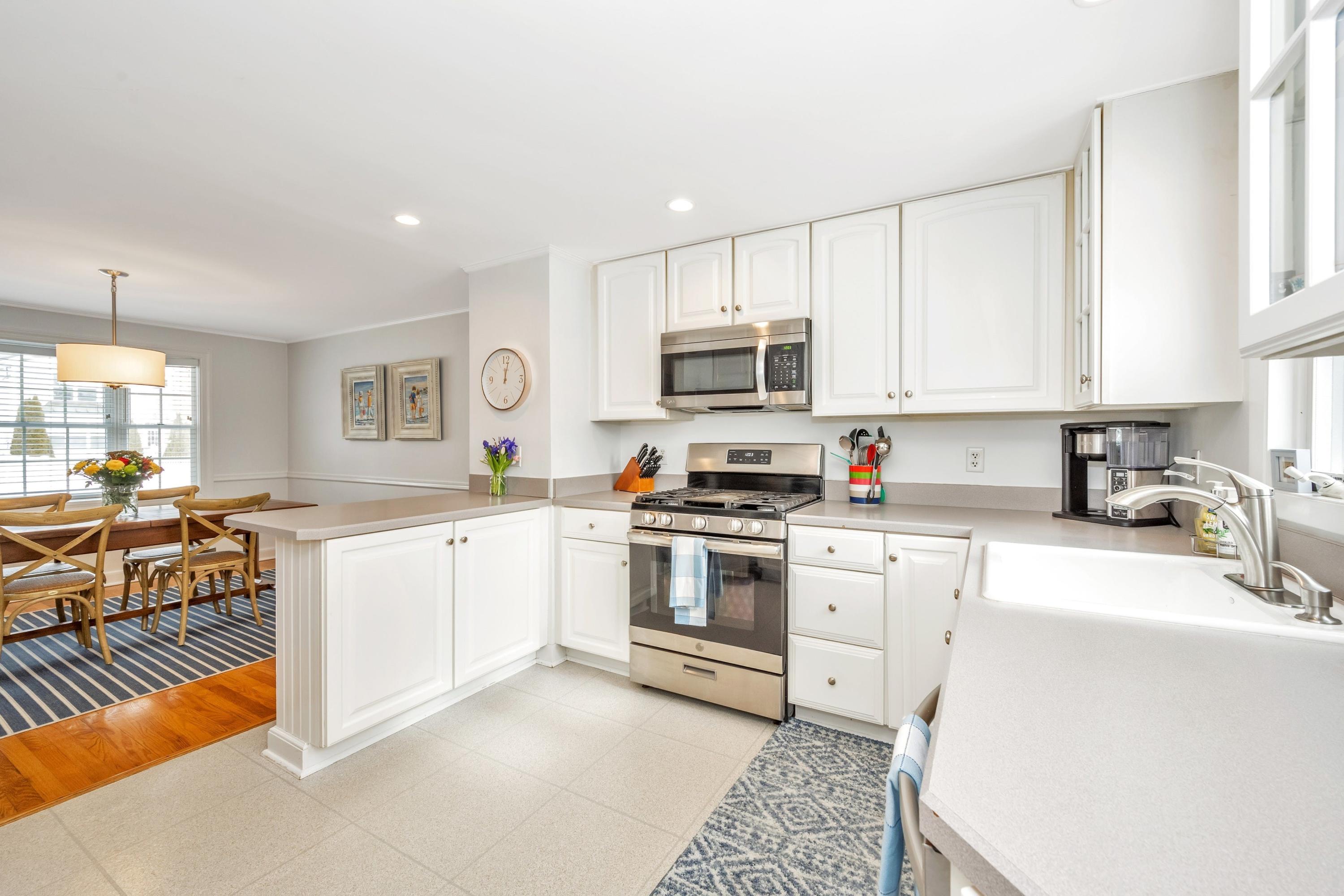 879 Oldfield Road Fairfield, CT 06824 - Photo 10 of 26 a kitchen with stainless steel appliances granite countertop a stove top oven a sink a dining table and chairs with white cabinets