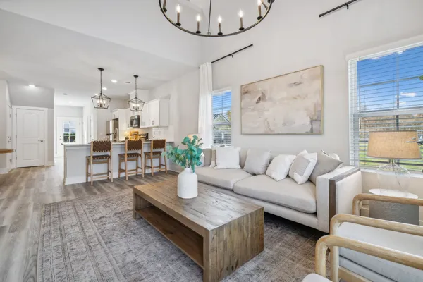 a living room with furniture a chandelier and a dining table with wooden floor
