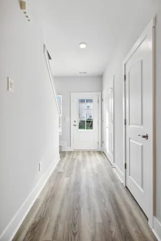 a kitchen with stainless steel appliances a stove a sink dishwasher a refrigerator white cabinets and chairs with wooden floor