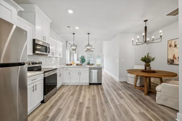 a kitchen with stainless steel appliances granite countertop a refrigerator stove a sink and white cabinets