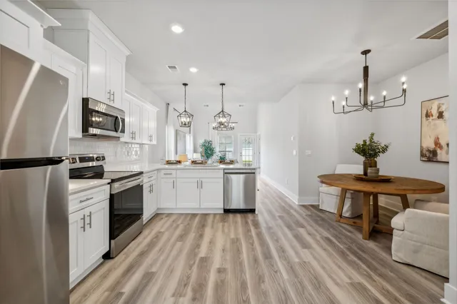 a kitchen with stainless steel appliances granite countertop a refrigerator stove a sink and white cabinets