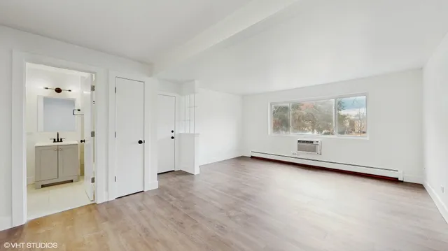 a view of an empty room with a window and wooden floor