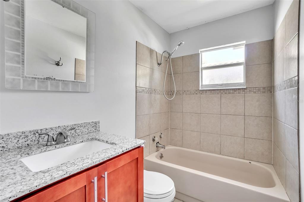 10626 Deergrass Lane Orlando, FL 32821 - Photo 21 of 41 a bathroom with a granite countertop sink a toilet and bathtub